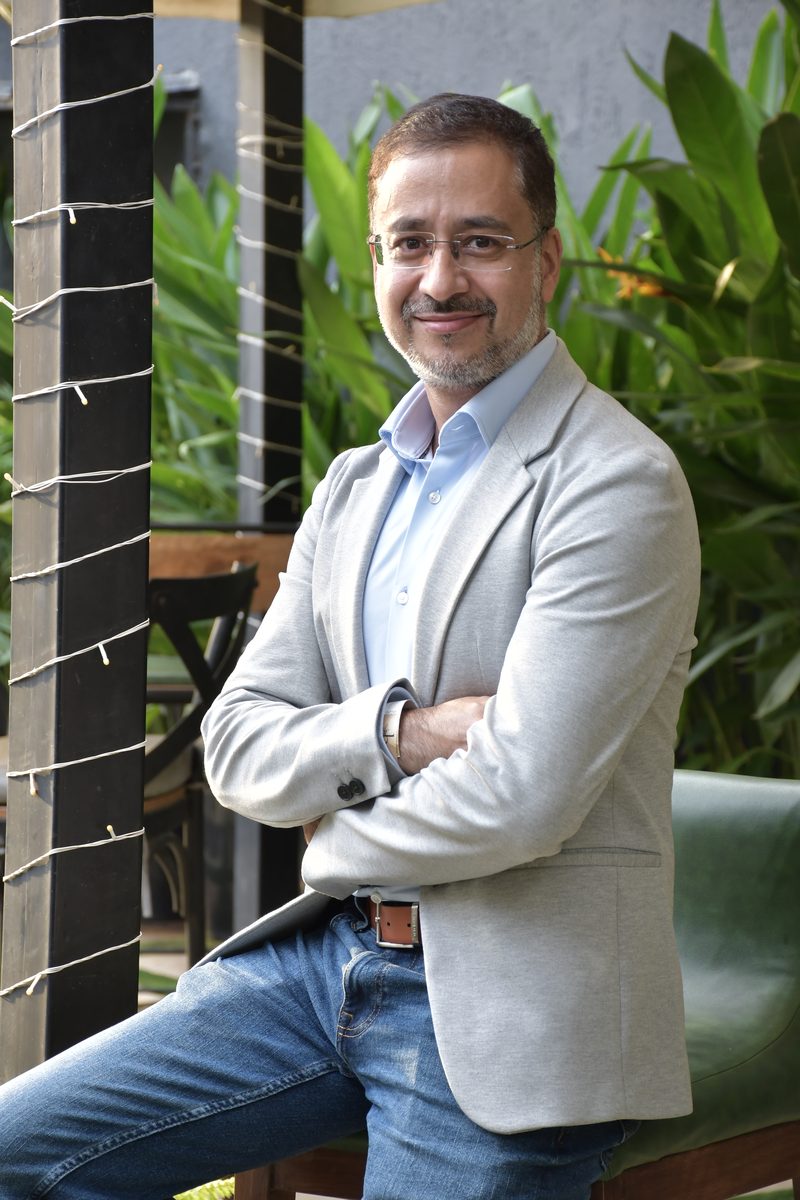 Avinash Kaul in a light blazer and jeans, arms crossed, smiling in a relaxed outdoor setting